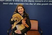 Annie Fuelle sitting in a chair holding a golden retriever puppy.