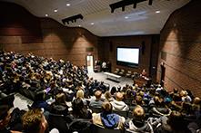 image of a lecture hall filled with people listening to a speaker
